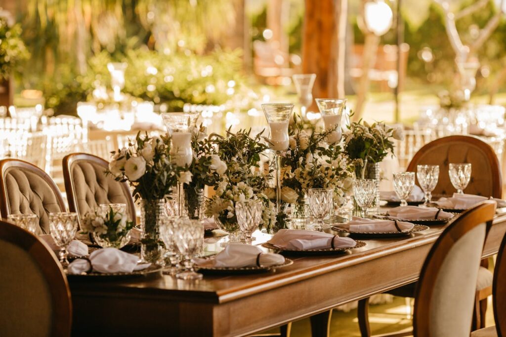 Elegant outdoor wedding reception with beautifully set table, flowers, and glasses.